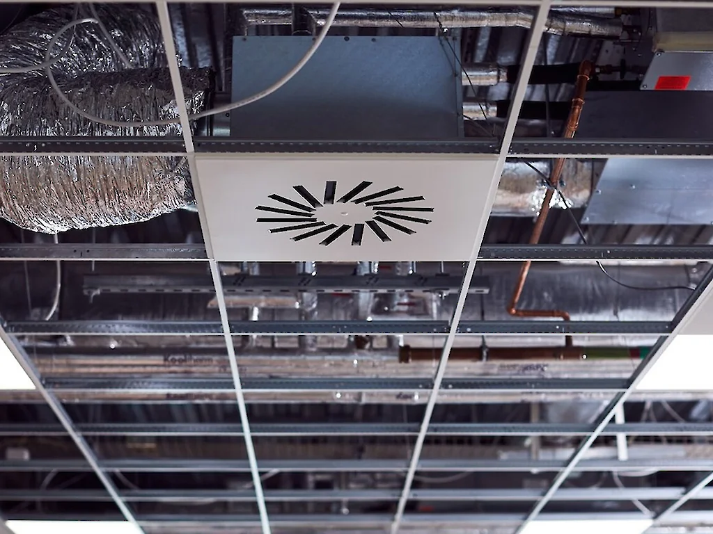 Services above a suspended grid ceiling: rectangular ductwork, insulated pipework and cable tray.